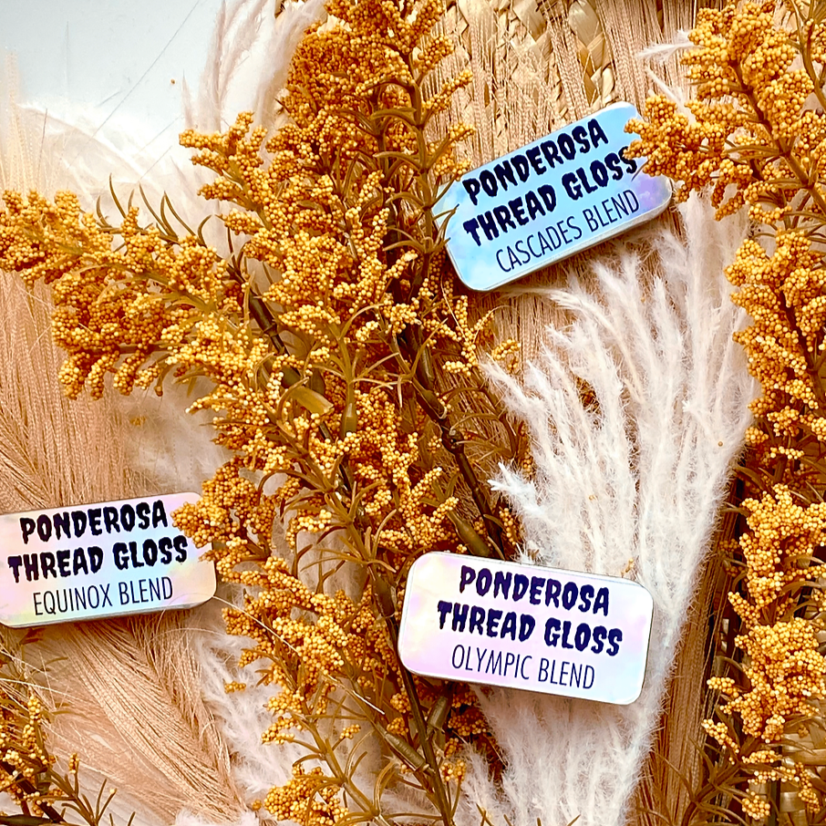 Several tins of Ponderosa Thread Gloss scattered against a background of dried flowers.