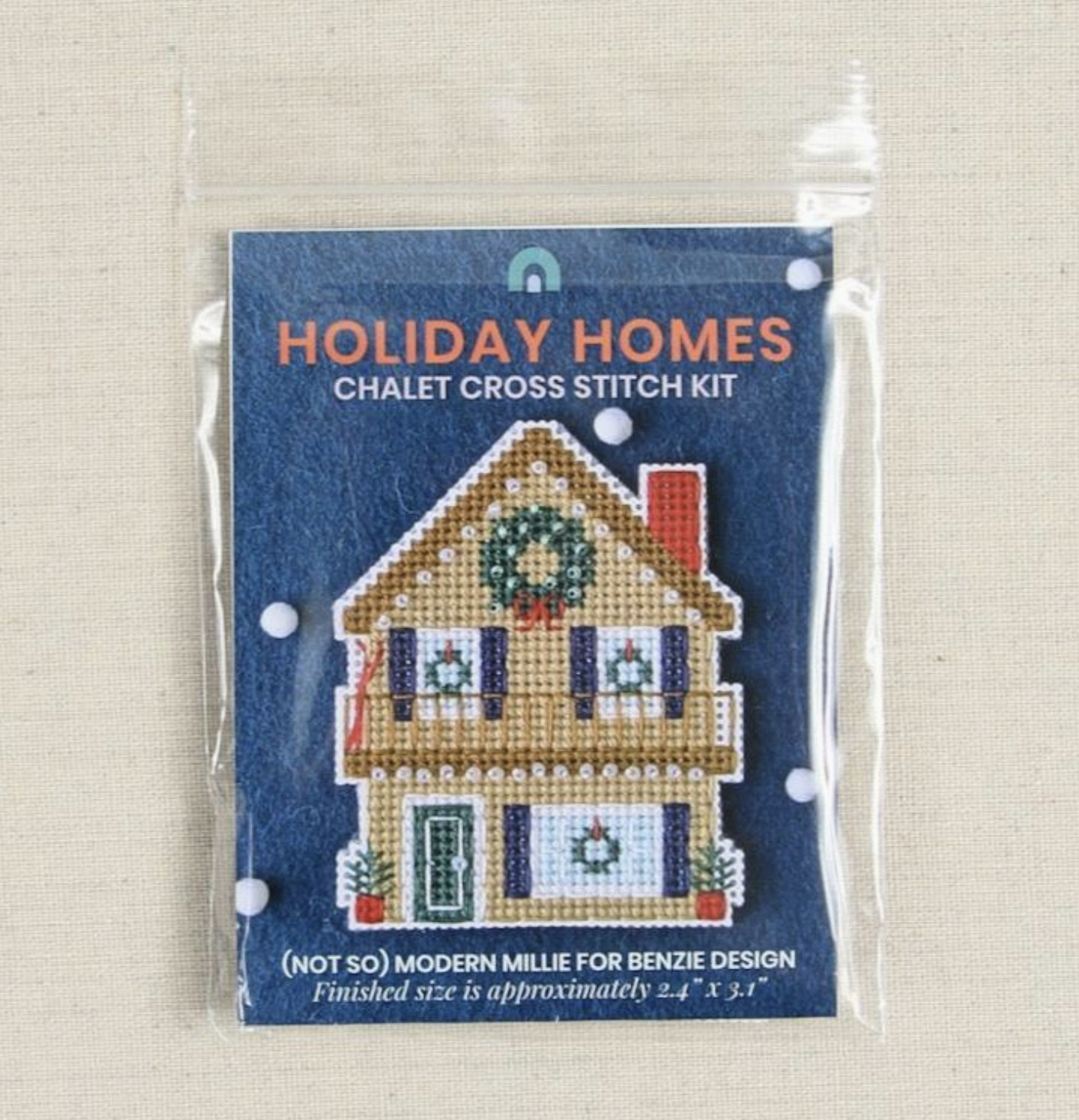 The Holiday Homes chalet cross stitch kit laying flat on a table in the packaging. 