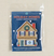 The Holiday Homes chalet cross stitch kit laying flat on a table in the packaging. 