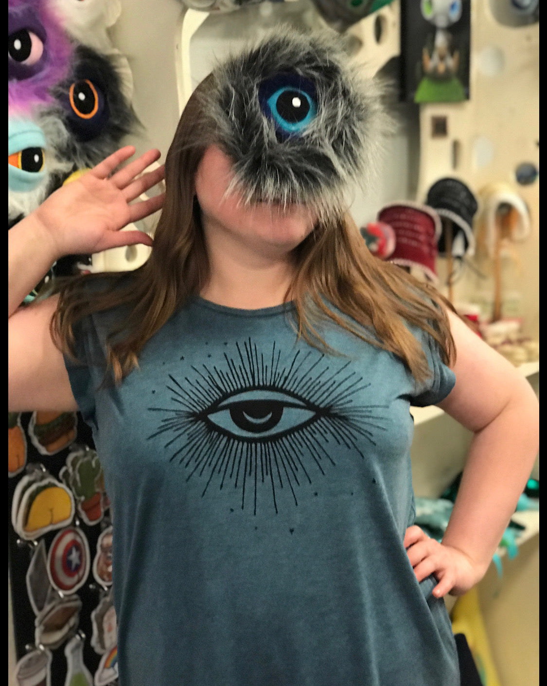 Person wearing teal blue muscle shirt - loose fitting - and with a furry monster eyeball covering their face.
