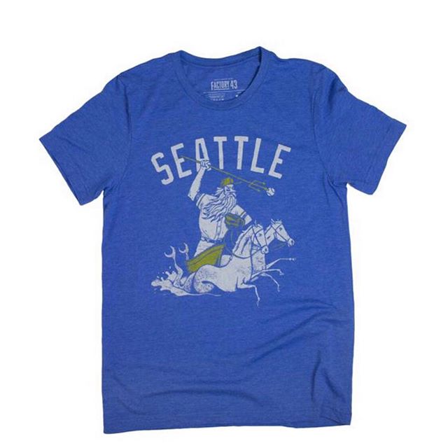 Blue unisex crew t-shirt by Factory 43. It says Seattle and has a mariner wearing a baseball hat and glove and being pulled by two horse mermaids. 