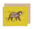 A mustard yellow card shows an image of a brown bear with rosy cheeks. It says "Happy Birthday" across his body. Bees and a hive are in the background along with some greenery. The card is shown on a white background with a Kraft colored envelope behind it.