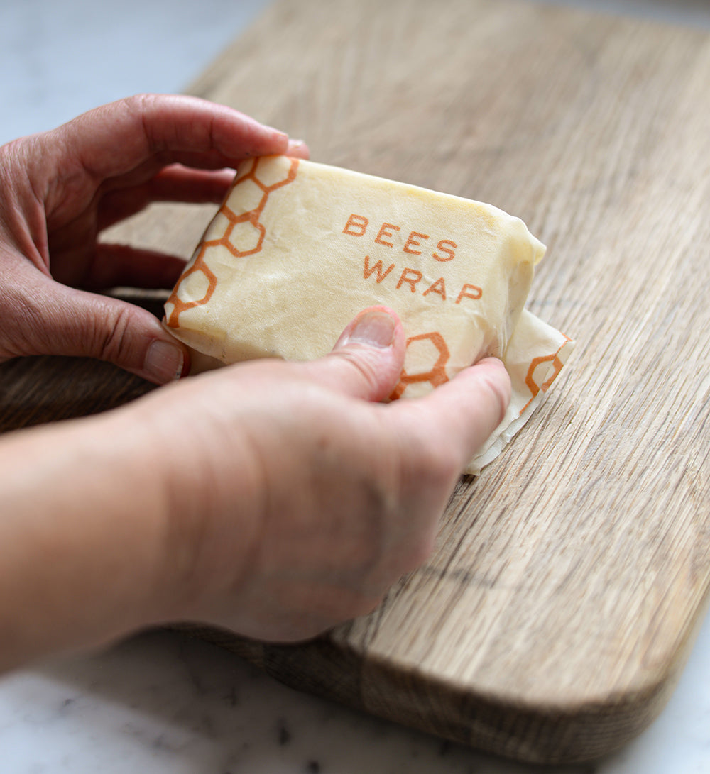 Photo by Jack Cole on Unsplash. Hands holding a block of cheese wrapped in a beeswax wrap.