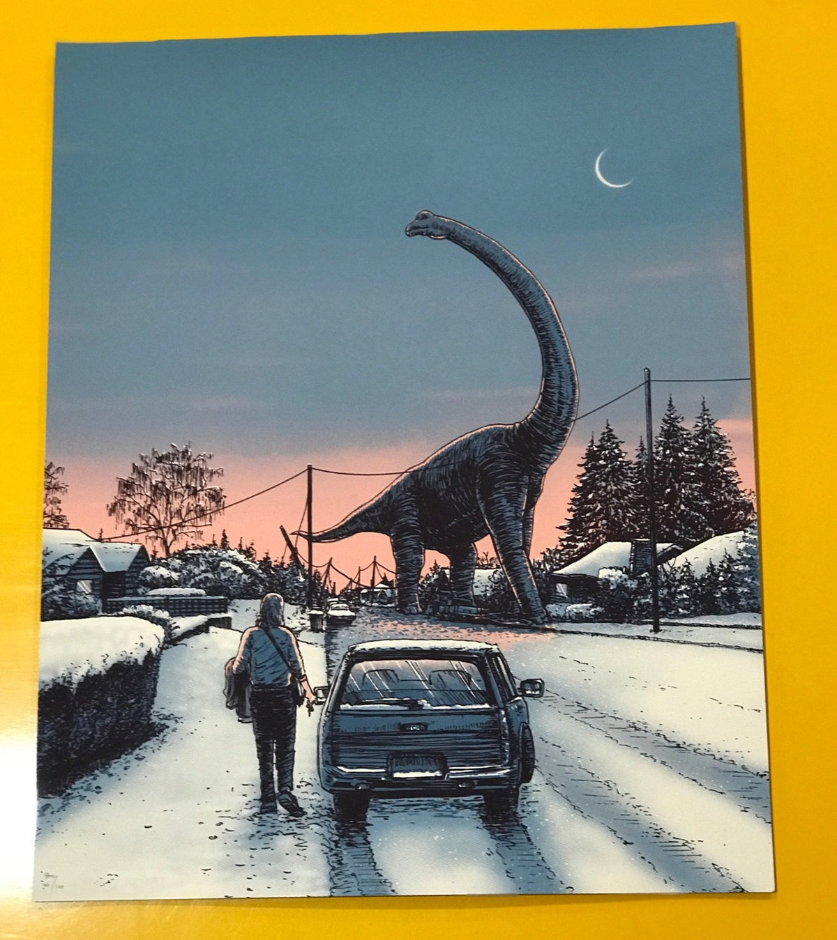 A person stands by their stopped car, while a longnecked dinosaur crossed the road. The road, houses and surrounding trees are covered with snow. There is a crescent moon in the blue night sky and a pink haze near the bottom as the sun goes down.