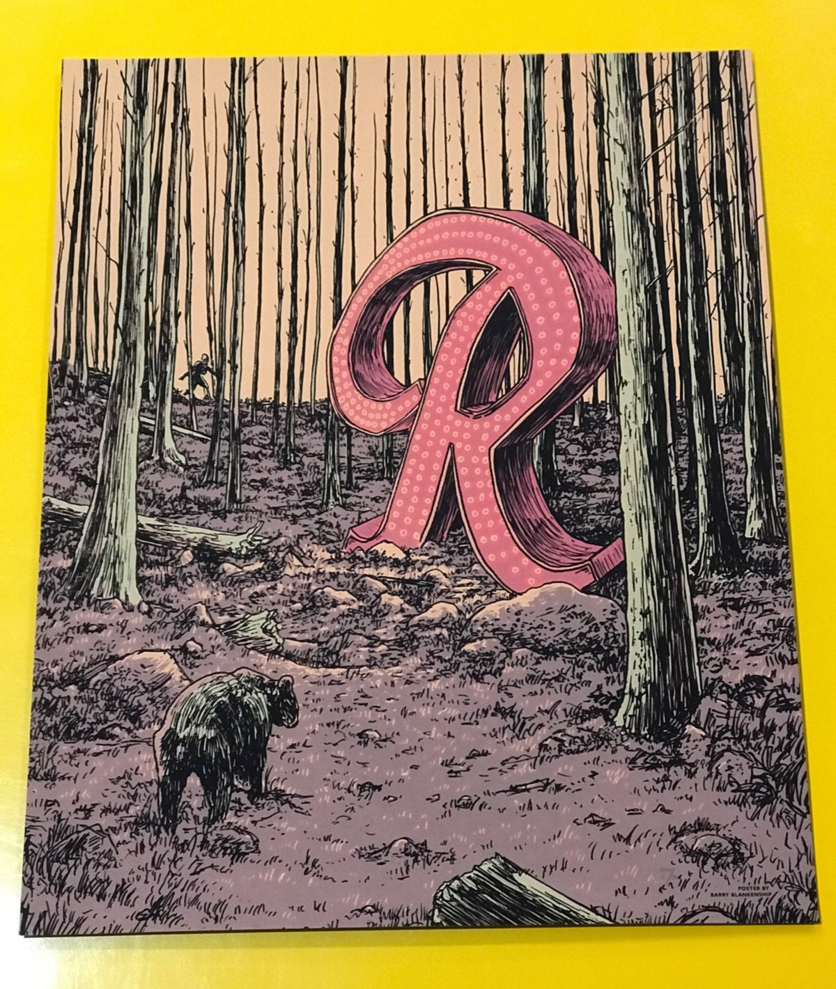 A large marquee lighted R is left in a barren forest. A bear happens upon it. Looks like it could be the end of times. 